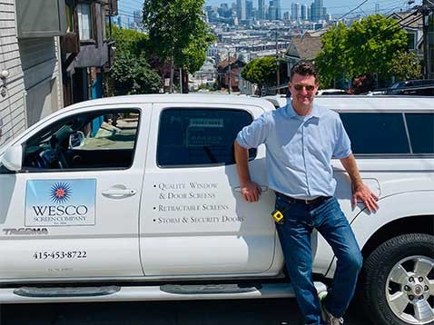 A smiling man leaning against the company truck