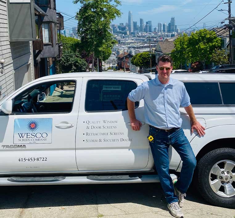 A smiling man leaning against the company truck
